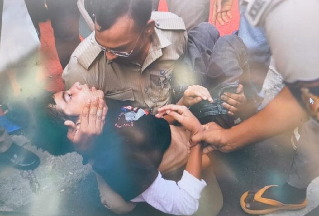 Police officer supports unconscious boy during chaos outside Bengaluru stadium.